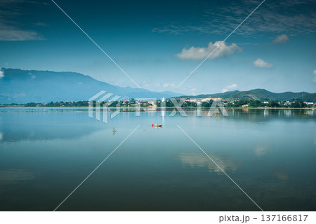 Tranquil lake with mountain and villager boat on sunny day Tranquil lake with mountain and villager boat on sunny day 137166817