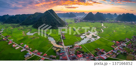 Colorful sunset over Bac Son Valley with mountains, lush green fields, winding river and village in Vietnam Colorful sunset over Bac Son Valley with mountains, lush green fields, winding river and village in Vietnam 137166852