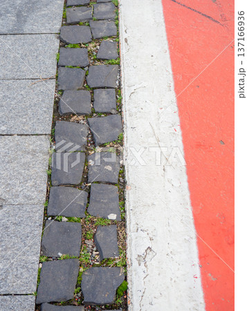Border between running track and street paving stones. Treadmill concept. Surface for cycling. Infrastructure of a modern city. Border between running track and street paving stones. Treadmill concept. Surface for cycling. Infrastructure of a modern city. 137166936