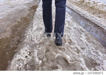 Spring slush. People walks along a snowy road, the snow melts 137166971