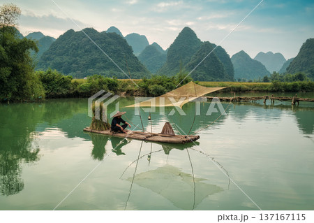 Rural scene of fisherman fishing on wooden raft, surrounded by mountain in sunny day at Phong Nam valley 137167115