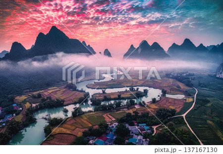 Dramatic sunrise over mountain range with foggy on rural village and river flows through in Phong Nam Valley Dramatic sunrise over mountain range with foggy on rural village and river flows through in Phong Nam Valley 137167130