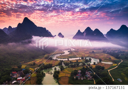 Dramatic sunrise over mountain range with foggy on rural village and river flows through in Phong Nam Valley at Cao Bang, Vietnam 137167131