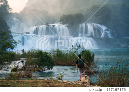 Ban Gioc Waterfall flowing with male tourist standing on the rock 137167176