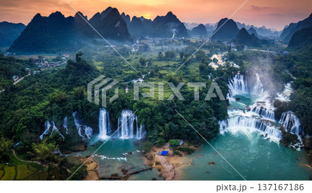 Sunset over mountain range with Ban Gioc waterfall flowing in tropical rainforest at Vietnam 137167186