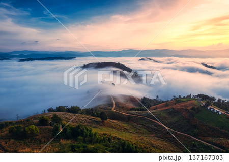 Sunrise over sea of fog flowing over mountain during harvest in countryside Sunrise over sea of fog flowing over mountain during harvest in countryside 137167303