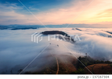 Sunrise over sea of fog flowing over mountain during harvest in countryside Sunrise over sea of fog flowing over mountain during harvest in countryside 137167304