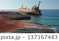 Young girl and others on rocky Paphos coastline watching the stranded Edro III cargo ship against clear blue Mediterranean waters and a bright summer sky, travel and nature clash 137167483