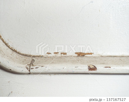 Part of an old door. White paint is coming off the wood. Surface with peeling paint. 137167527