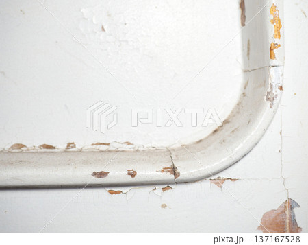 Part of an old door. White paint is coming off the wood. Surface with peeling paint. 137167528