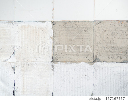 background of broken white tiles. The wall needs repairs. The concept of ruin and abandonment. Chipped tile. 137167557