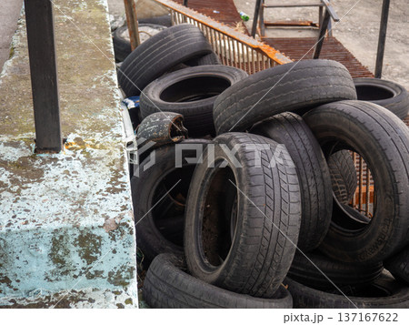 pile of dumped used car tires. Lots of rubber. Tire dump. Industrial zone. Next to the auto repair shop. 137167622