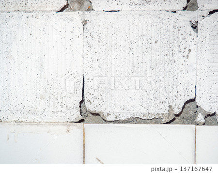 background of broken white tiles. The wall needs repairs. The concept of ruin and abandonment. Chipped tile. background of broken white tiles. The wall needs repairs. The concept of ruin and abandonment. Chipped tile. 137167647