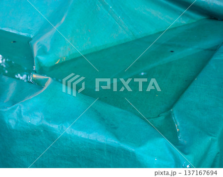 Water has accumulated on the tarp. Green protective oilcloth. 137167694