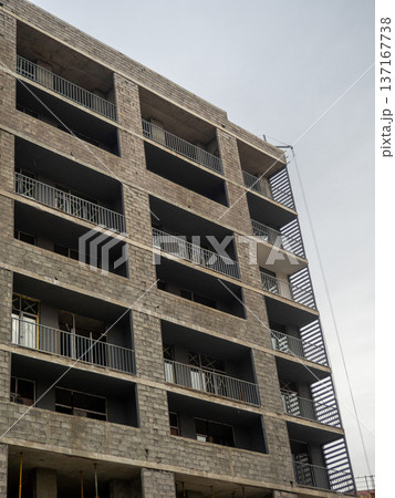 A gloomy gray building. Unfinished brutalist house. Concept of crisis in construction. Gray architecture. Cloudy autumn weather. Concrete house for people. A gloomy gray building. Unfinished brutalist house. Concept of crisis in construction. Gray architecture. Cloudy autumn weather. Concrete house for people. 137167738