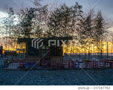 Restaurant on the seashore at sunset. sea coastal landscape. Restaurant at the resort. A thatched hut surrounded by bamboo Restaurant on the seashore at sunset. sea coastal landscape. Restaurant at the resort. A thatched hut surrounded by bamboo 137167762
