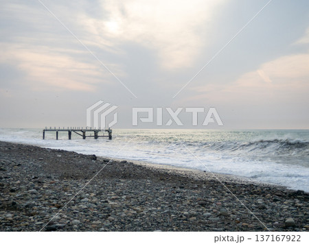 Destroyed pier under the waves. Bad weather at sea. Beautiful seashore with old architecture Destroyed pier under the waves. Bad weather at sea. Beautiful seashore with old architecture 137167922