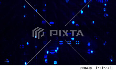 Abstract closeup of blue LED dots glowing through a dark grid, soft bokeh and deep shadows creating a futuristic mood. Digital light patterns inspire creativity, yet screen exposure can affect sleep. 137168311