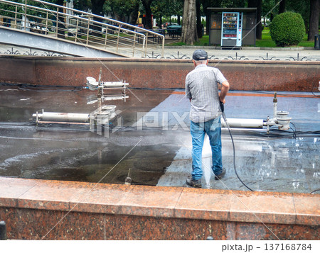 Empty fountain in a city park. Dehumidification. Cleaning the fountain with a hose. The device of the fountain. Pipes for water supply. Water hoses. Modern technologies. Infrastructure maintenance. Empty fountain in a city park. Dehumidification. Cleaning the fountain with a hose. The device of the fountain. Pipes for water supply. Water hoses. Modern technologies. Infrastructure maintenance. 137168784