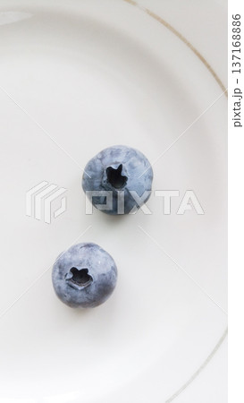 Two blueberries on a plate. Two blueberries on a plate. 137168886