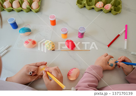 Top View of Kids Hands Drawing on Easter Eggs with Markers 137170139