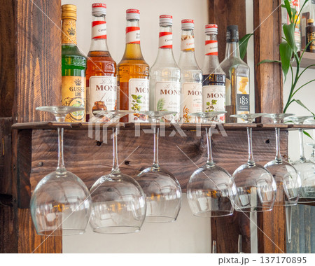 Glasses hang over the bar counter. The glasses are turned upside down. restaurant interior. Concept of drinking alcoholic beverages. Glass glasses for wine. Night club in daylight Glasses hang over the bar counter. The glasses are turned upside down. restaurant interior. Concept of drinking alcoholic beverages. Glass glasses for wine. Night club in daylight 137170895