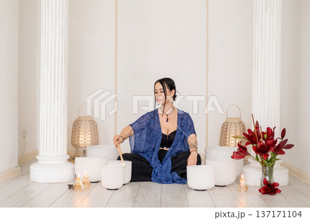 Therapy meditation. Healing crystal singing. Female playing sound white bowls wellness retreat candles for spiritual calming treatment. Therapy meditation. Healing crystal singing. Female playing sound white bowls wellness retreat candles for spiritual calming treatment. 137171104