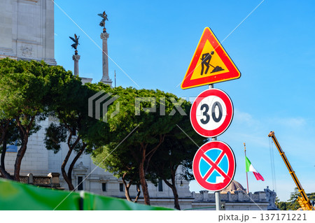 Traffic signs show road work and speed limit near historic building in city center 137171221