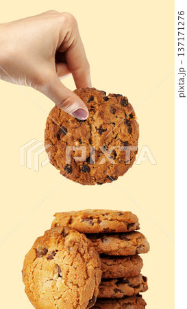 Hand reaching for a chocolate chip cookie from a stack of cookies for Easter celebration Hand reaching for a chocolate chip cookie from a stack of cookies for Easter celebration 137171276