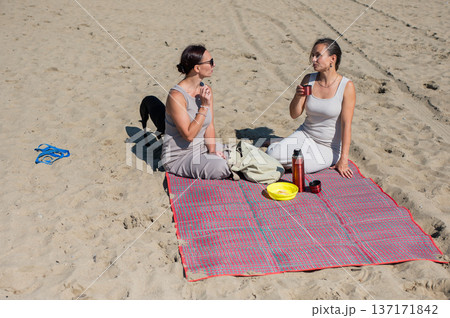 Two Caucasian women on a picnic on the beach.  137171842