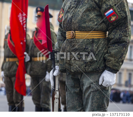 Military field uniform Russian soldier during parade rehearsal, with colors of national flag in background. Military field uniform Russian soldier during parade rehearsal, with colors of national flag in background. 137173110