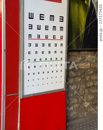 Vision test chart outside optician office. Eye examination, healthcare and optical diagnostics in urban environment. Vision test chart outside optician office. Eye examination, healthcare and optical diagnostics in urban environment. 137173428