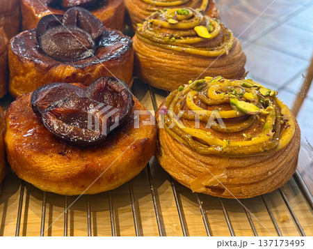 Assorted pastries with plums, and pistachios in bakery display close-up. Sweetness, texture, and craftsmanship in artisanal dessert presentation. Assorted pastries with plums, and pistachios in bakery display close-up. Sweetness, texture, and craftsmanship in artisanal dessert presentation. 137173495