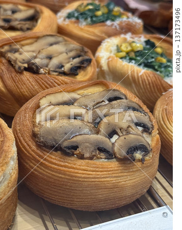 Freshly baked pastries with mushrooms and vegetables in bakery display close-up. Savory flavors, texture, and craftsmanship in gourmet patisserie. Freshly baked pastries with mushrooms and vegetables in bakery display close-up. Savory flavors, texture, and craftsmanship in gourmet patisserie. 137173496