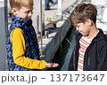 Two boys looking at seashell in open palm at marina, childhood curiosity, coastal exploration and discovery 137173647