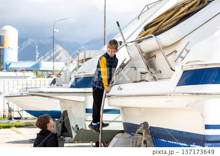 Boy climbing ladder on yacht in dry dock, childhood adventure, learning and independence outdoors 137173649