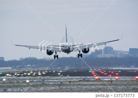 View from behind of a commercial plane touching down on a lit runway during blue hour 137173773