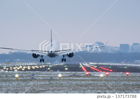 Large passenger jet landing at a snowy airport during winter evening hours 137173788