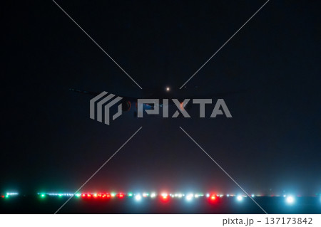 Silhouette of commercial airplane with landing lights visible against dark sky over airport landing field Silhouette of commercial airplane with landing lights visible against dark sky over airport landing field 137173842