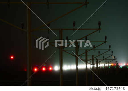 Yellow approach light structures standing in the mist at the edge of an airport runway during nighttime Yellow approach light structures standing in the mist at the edge of an airport runway during nighttime 137173848