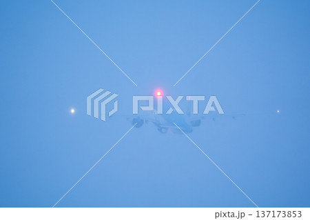 Silhouette of a passenger jet with red beacon light visible while flying into heavy fog after takeoff Silhouette of a passenger jet with red beacon light visible while flying into heavy fog after takeoff 137173853
