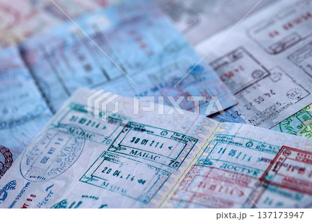 Big amount of passport pages full of colorful stamps after travel and border crossing. Tourism and border control concept. Immigration and travel around the world Big amount of passport pages full of colorful stamps after travel and border crossing. Tourism and border control concept. Immigration and travel around the world 137173947