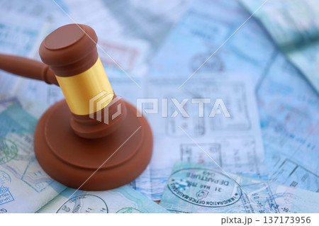 Judgement gavel on passport pages full of colorful stamps after travel and tourism. Border control and lawsuit concept. Immigration and travel around the world Judgement gavel on passport pages full of colorful stamps after travel and tourism. Border control and lawsuit concept. Immigration and travel around the world 137173956