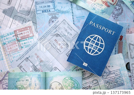 One fictional passport on big amount of passport pages full of colorful stamps after travel and border crossing. Tourism and border control concept. Immigration and travel around the world 137173965
