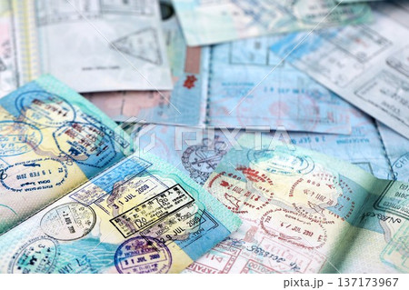 Big amount of passport pages full of colorful stamps after travel and border crossing. Tourism and border control concept. Immigration and travel around the world Big amount of passport pages full of colorful stamps after travel and border crossing. Tourism and border control concept. Immigration and travel around the world 137173967