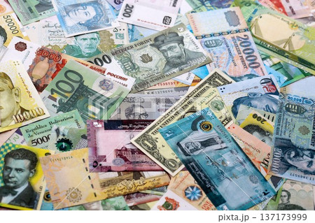 Different colorful banknotes from many various currencies of the world. Currency Exchange concept. Big stack of money bills Different colorful banknotes from many various currencies of the world. Currency Exchange concept. Big stack of money bills 137173999