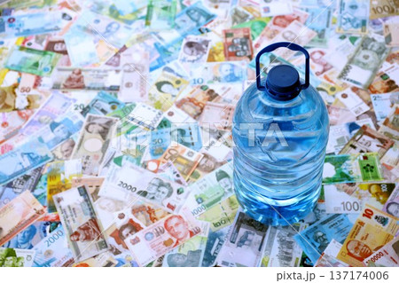 Big plastic bottle of water lies of big amount of money bills banknotes from various currencies over the whole world. Big plastic bottle of water lies of big amount of money bills banknotes from various currencies over the whole world. 137174006