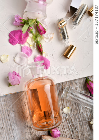 perfume empty bottles and essence around roses settled at authentic provence background. Perfumer, beauty and trendy concept. flat lay perfume empty bottles and essence around roses settled at authentic provence background. Perfumer, beauty and trendy concept. flat lay 137174187