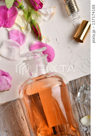 perfume essence around roses settled at authentic provence background. Perfumer, beauty and trendy concept. flat lay perfume essence around roses settled at authentic provence background. Perfumer, beauty and trendy concept. flat lay 137174188
