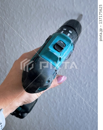 A woman's hand holding a cordless drill-driver, top view A woman's hand holding a cordless drill-driver, top view 137175625